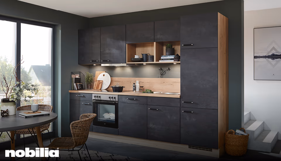 Moderne Nobilia Küchenzeile in Anthrazit mit offenen Holzregalen, warmem Beleuchtungskonzept und integriertem Essplatz, ideal für stilvolles Wohnen und funktionale Küchenplanung.